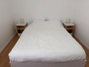 a bedroom with a white bed with two night stands at Appartement Voltaire in Romilly-sur-Seine +24 photos