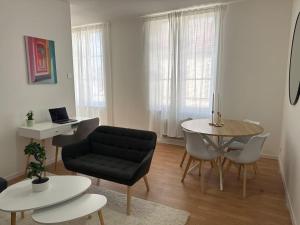 a living room with a black couch and a table at Appartement Voltaire in Romilly-sur-Seine