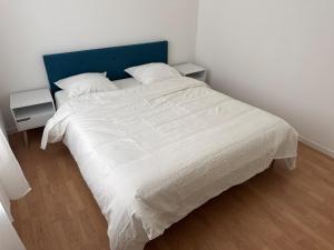 a white bed with a blue headboard in a bedroom at Appartement Voltaire in Romilly-sur-Seine