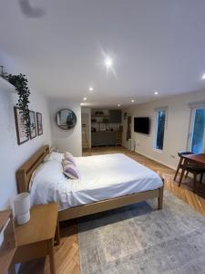 a bedroom with a large white bed and a table at The Summerhouse in Cheadle