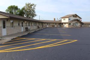 a parking lot with yellow lines in front of a building at The Perrysburg Budget Inn in Millbury