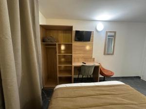 a room with a bed and a desk with a television at NOROTEL Eco in Brumath