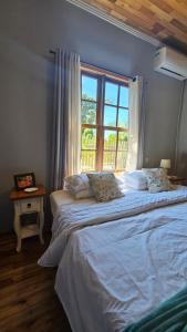 a bedroom with a large bed with a window at Hospedaria Casa Verde in Itapoa