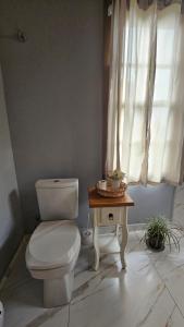a bathroom with a toilet and a table and a window at Hospedaria Casa Verde in Itapoa +20 photos