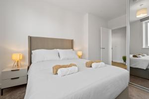 a bedroom with a large white bed with two stuffed animals on it at Luxury 2BR Staines 12 Mins to Heathrow & Thames in Staines