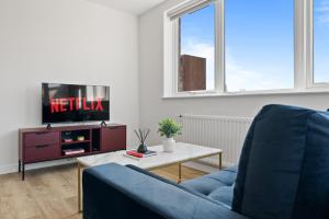 a living room with a tv and a blue couch at Luxury 2BR Staines 12 Mins to Heathrow & Thames in Staines