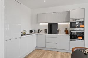 a white kitchen with white cabinets and appliances at Luxury 2BR Staines 12 Mins to Heathrow & Thames in Staines