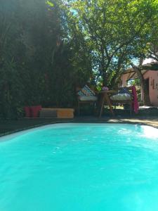 a large blue swimming pool with a table and a chair at Casa Flor in Ilha de Boipeba +10 photos