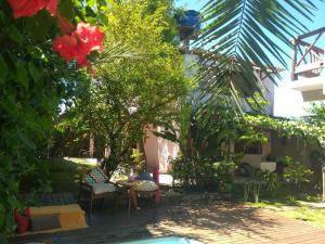 a garden with a table and chairs and a tree at Casa Flor in Ilha de Boipeba