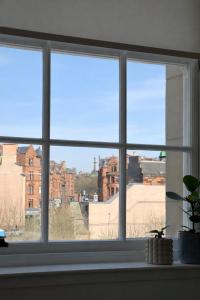 a window with a view of a city through it at Luxury Historic City-Centre Flat & Free Parking in Glasgow