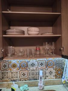 a kitchen cabinet with plates and glasses on shelves at Chico's House in Uruguaiana
