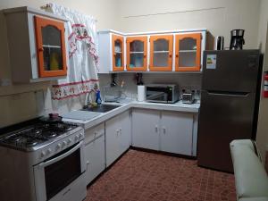a kitchen with white cabinets and a black refrigerator at Vincy vybz in Kingstown +5 photos