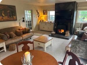a living room with a couch and a table with a fireplace at Stunning country home with private wellness Spa in Strachur