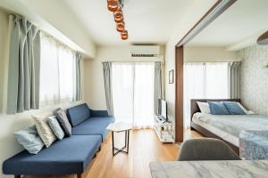 a bedroom with a bed and a couch and windows at The Peak Tengachaya 605 KIX Direct Cozy Elegance near Namba in Osaka