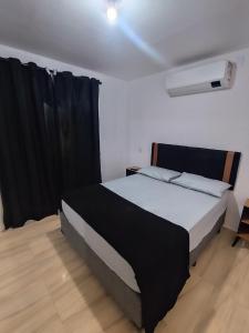 a bedroom with a large bed with black curtains at Microcasa com ar em Resende in Resende