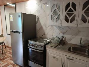 a kitchen with a refrigerator and a stove and a sink at Refugio Rancagua in Pueblo de Naturales