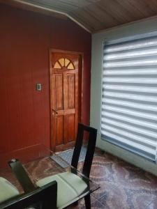 a room with a door and a table and a chair at Refugio Rancagua in Pueblo de Naturales