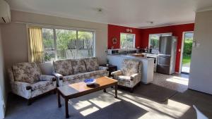 a living room with two chairs and a table at Hooked On Tiki in Coromandel Town