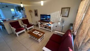 a living room with a couch and chairs and a tv at Duplex Jauregui en Lujan in Luján