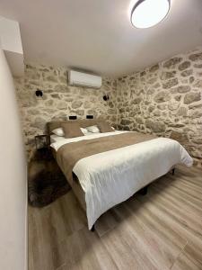 a bedroom with a large bed and a stone wall at Apartman Roza in Konjic