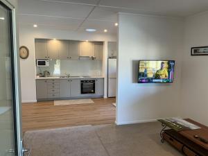 a living room with a kitchen with a tv on a wall at River and Mountain Central in Queensberry