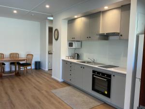 a kitchen with white cabinets and a table and a dining room at River and Mountain Central in Queensberry +3 photos