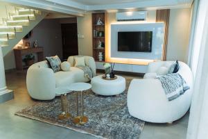 a living room with white furniture and a flat screen tv at Tlou Luxe stay in Gaborone