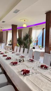 a long table with white chairs and wine glasses at Hotel Kanione in Çorovodë