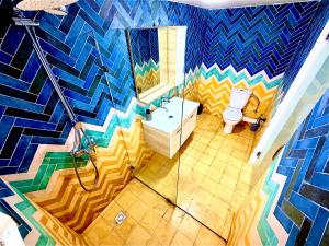 a bathroom with a toilet and a mosaic wall at Oualidia surflodge in Oualidia +36 photos