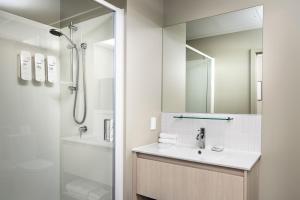 a white bathroom with a sink and a shower at Quest 256 Lambton in Wellington +18 photos