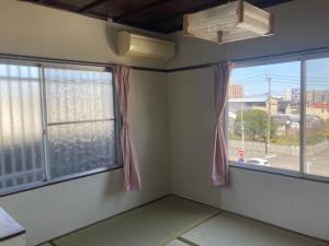 a room with two windows with a view of a city at Oita City Vacation Condominium in Oita