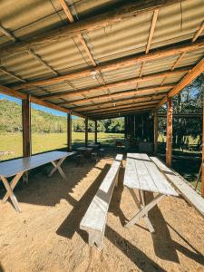 a picnic table and benches in a pavilion at Pousada e Camping São Matheus in Lauro Müller