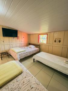 a room with three beds and a flat screen tv at Pousada e Camping São Matheus in Lauro Müller