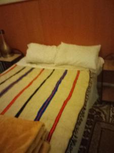 a bed with a colorful blanket and pillows on it at Hôtel des cedresazrou in Azrou