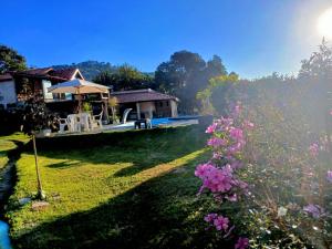 a garden with a house and some pink flowers at Chácara dos Ypes in Bueno Brandão