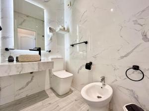 a white bathroom with a toilet and a sink at 360 Oceanfront & Sunset View Condo - Terrace & 2BR in Tangier +17 photos