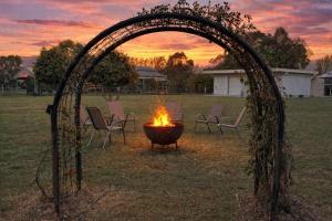 an arch with chairs around a fire in a field at Marignano Homestead in Broke