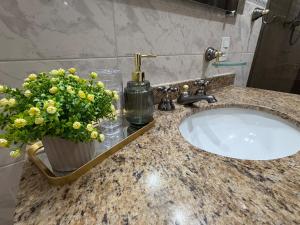 a bathroom sink with a vase of flowers on it at Amplo apartamento completo no Centro Cambuí in Campinas