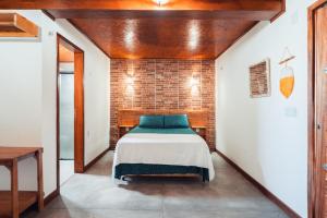 a bedroom with a bed and a brick wall at Villa Chalés - térreo in Barra Grande