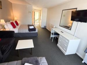 a hotel room with a bedroom with a bed and a tv at Champers Motor Inn in Lower Hutt