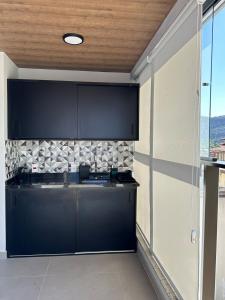 a kitchen with black cabinets and a wall at Piratininga a Beira Mar - Niterói in Niterói +25 photos