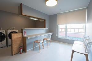 a kitchen with three chairs and a counter with a washer at B cycle Double Room in Biei