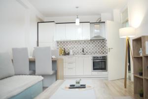 a small kitchen with white cabinets and a couch at Sweet Home in Kosovo Polje +7 photos