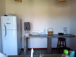 a kitchen with a table and a white refrigerator at Villa Chalés - andar superior in Barra Grande