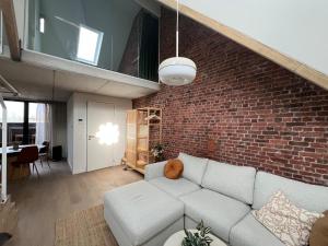 a living room with a white couch and a brick wall at Inviting apartment in Bree with terrace in Bree