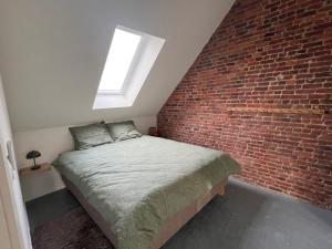 a bed in a room with a brick wall at Inviting apartment in Bree with terrace in Bree
