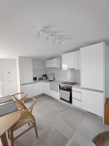 a kitchen with white cabinets and a table and chairs at Deluxe 2 Terraces River&Marina View Flat in Ferragudo