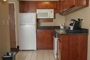 a kitchen with a white refrigerator and wooden cabinets at Quality Inn & Suites Downtown Mansfield in Mansfield +23 photos