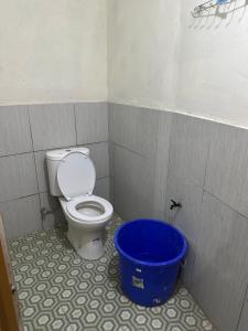 a bathroom with a toilet and a blue bucket at Homestay Joglo Kembar in Gading