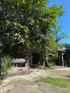 a building with a sign in front of a tree at Homestay Joglo Kembar in Gading